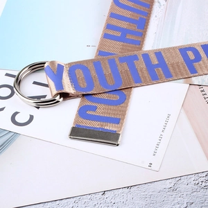 Détail d'une ceinture en toile kaki avec texte YOUTH violet et boucle argentée à double anneau D