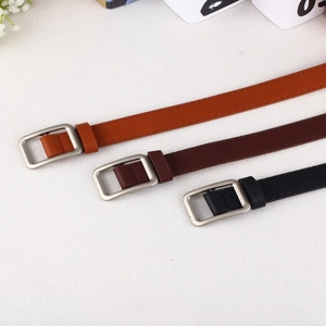 Detailed view of three slim belts in orange-brown, dark coffee, and black with silver buckles