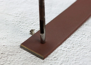 Gros plan détaillé du processus de poinçonnage DIY sur une ceinture en cuir marron foncé