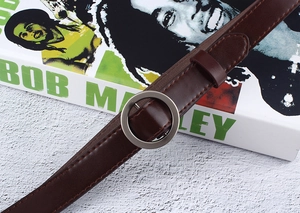 Close-up of dark brown leather belt with round metal buckle on textured background