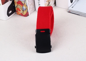 Detail of red woven canvas belt with a matte black metal buckle on white surface