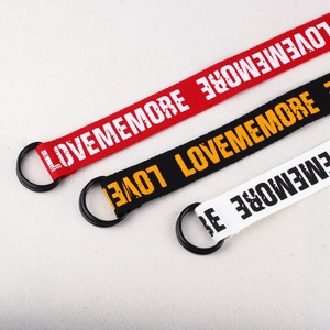 Détail de trois ceintures en toile rouge, noire et blanche avec double boucle en D noire