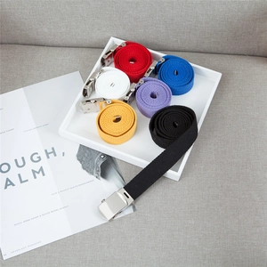 Flat lay of colorful canvas belts with silver metal buckles on a minimalist magazine tray