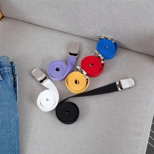 Close-up of assorted colorful canvas belts with polished silver buckles on a fabric sofa