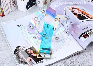 Détail de la ceinture en PVC holographique avec œillets métalliques et boucle carrée argentée