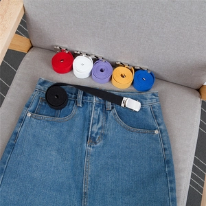 Close-up of a colorful woven canvas belt with a silver metal buckle on denim clothing
