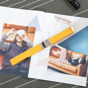 Detail of bright yellow canvas belt with silver polished buckle on a fashion magazine