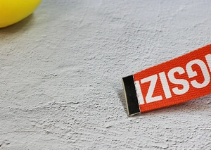 Close-up of orange woven nylon belt strap with white text print and silver metal clip buckle