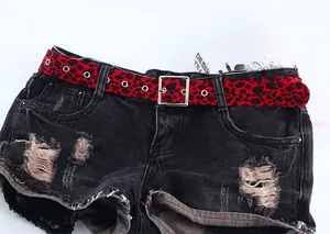 Détail de la ceinture rouge à imprimé léopard avec boucle en métal sur un short en jean