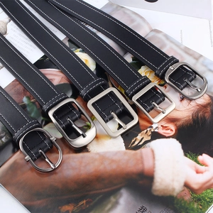 Détail de cinq ceintures en cuir noir avec surpiqûres blanches et boucles en métal