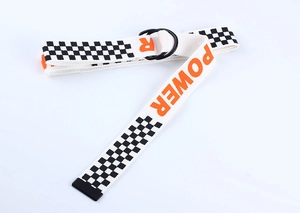 Détail de la ceinture en toile à carreaux avec lettrage orange et boucle double D en métal
