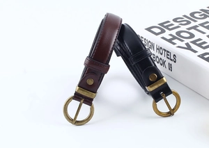 Dettaglio di cinture in pelle vintage nere e marroni con fibbie in ottone tondo