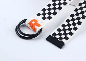 Détail de la ceinture en toile damier avec boucles doubles D et impression R orange