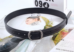 Détail d'une ceinture noire avec surpiqûres blanches et boucle ovale à strass
