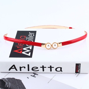 Elegant thin red skinny leather belt with pearl gold buckle on white minimalist background