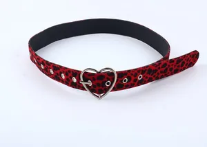 Détail de la ceinture à imprimé léopard rouge avec boucle cœur en métal argenté