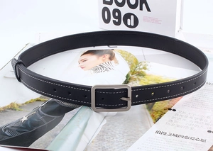 Détail d'une ceinture noire avec boucle carrée argentée et surpiqûres blanches contrastées