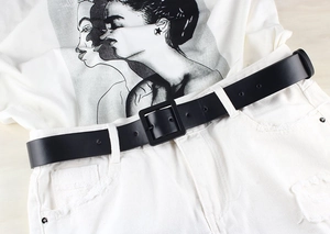 Close-up of a minimalist black belt with a square pin buckle on white denim trousers