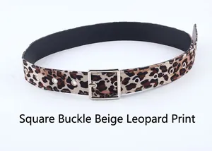 Détail de la boucle carrée argentée et motif léopard sur une ceinture blanc cassé