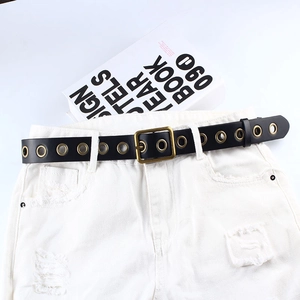 Ceinture polyvalente en similicuir noir avec œillets dorés sur un short blanc