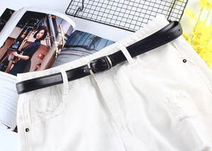 Détail d'une ceinture en similicuir noir avec boucle carrée sur un short blanc
