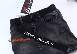 Close-up of black canvas belt with D-ring buckle and white slogan text on grey denim