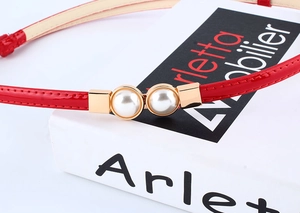 Detail of red patent leather belt with gold buckle and pearl embellishments