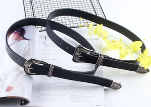 Western vintage black leather belt with ornate silver floral engraved buckle on magazine