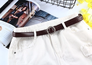 Détail de la ceinture fine en cuir PU marron avec boucle ronde argentée sur short