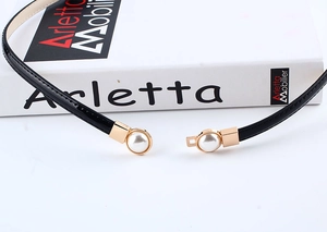 Detail of 1cm black patent leather skinny belt with gold metal and pearl tip