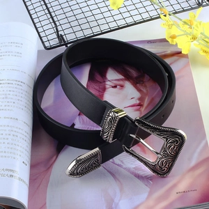 Vintage black leather belt with ornate silver floral buckle on fashion magazine background