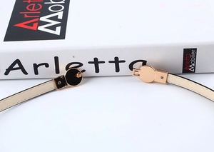 Close-up of a slim beige leather belt featuring a polished light gold round buckle detail