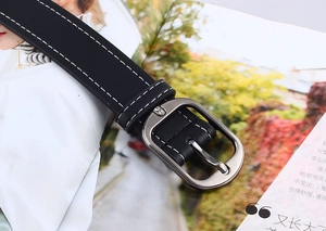 Gros plan détaillé d'une ceinture en cuir noir avec double couture blanche et boucle argent