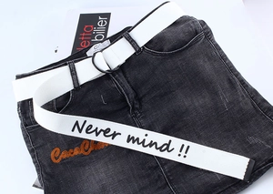 Detailed view of white canvas belt with black slogan and metal D-ring buckle