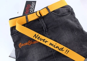 Detail of yellow canvas belt with double D-ring buckle and Never Mind printed slogan