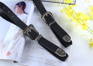 Detail of vintage silver carved buckle on black leather belt displayed on a magazine