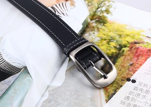 Détail de ceinture en cuir noir avec surpiqûres blanches et boucle carrée en métal mat