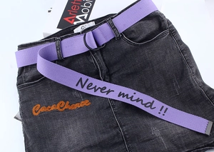 Macro shot of purple canvas belt with double D-ring buckle and printed lettering