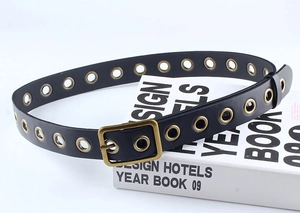 Détail d'une ceinture en similicuir noir avec œillets dorés et boucle vintage