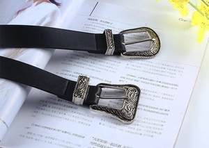 Detail of black leather belts with vintage silver engraved buckles on magazine background