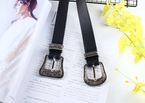 Detailed view of black leather belts with vintage silver floral engraved buckles on a magazine