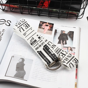 Close-up of white canvas belt with black letter print on a fashion magazine background