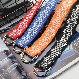 Close-up of canvas belts with double D-ring metal buckles and city names embroidery