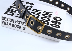 Détail de la ceinture punk en PU noir avec œillets dorés et boucle carrée sur support