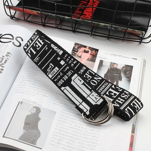 Detail of a black and white canvas belt with double D-ring buckle on a fashion magazine