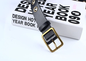 Détail d'une ceinture en cuir PU noir avec boucle bronze et décoration d'œillets en métal
