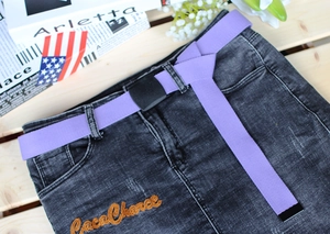 Detail of purple nylon canvas belt with matte black buckle on washed denim skirt