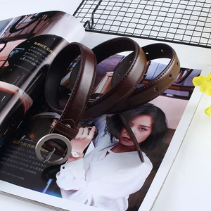 Détail de la ceinture en cuir PU marron foncé avec boucle ronde argentée sur un magazine