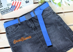 Detail of black denim skirt featuring an electric blue woven belt and orange embroidery