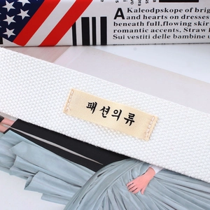 Close-up of white woven canvas belt with stitched Korean text label and textured fabric